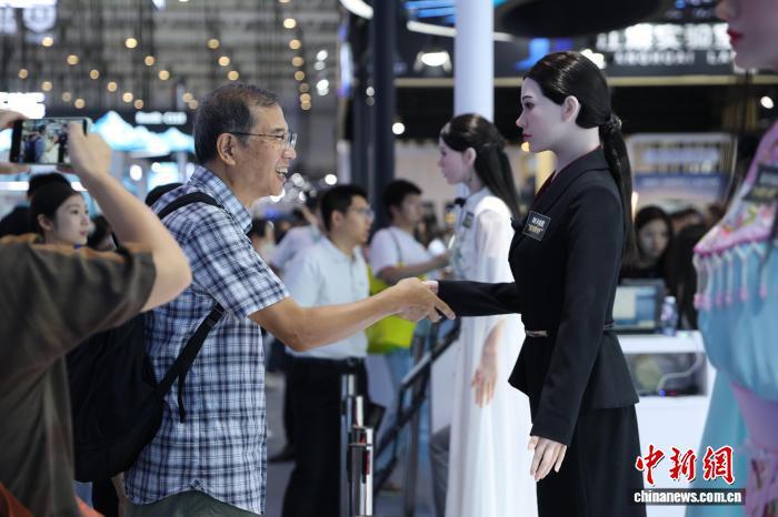 中新社记者拍摄的WRC 2026人形机器人销售员与观众握手场景
